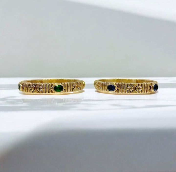 Two gold bangle bracelets set with green and blue gemstones