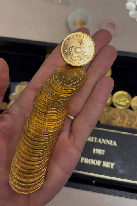 A hand holding a stack of gold coins